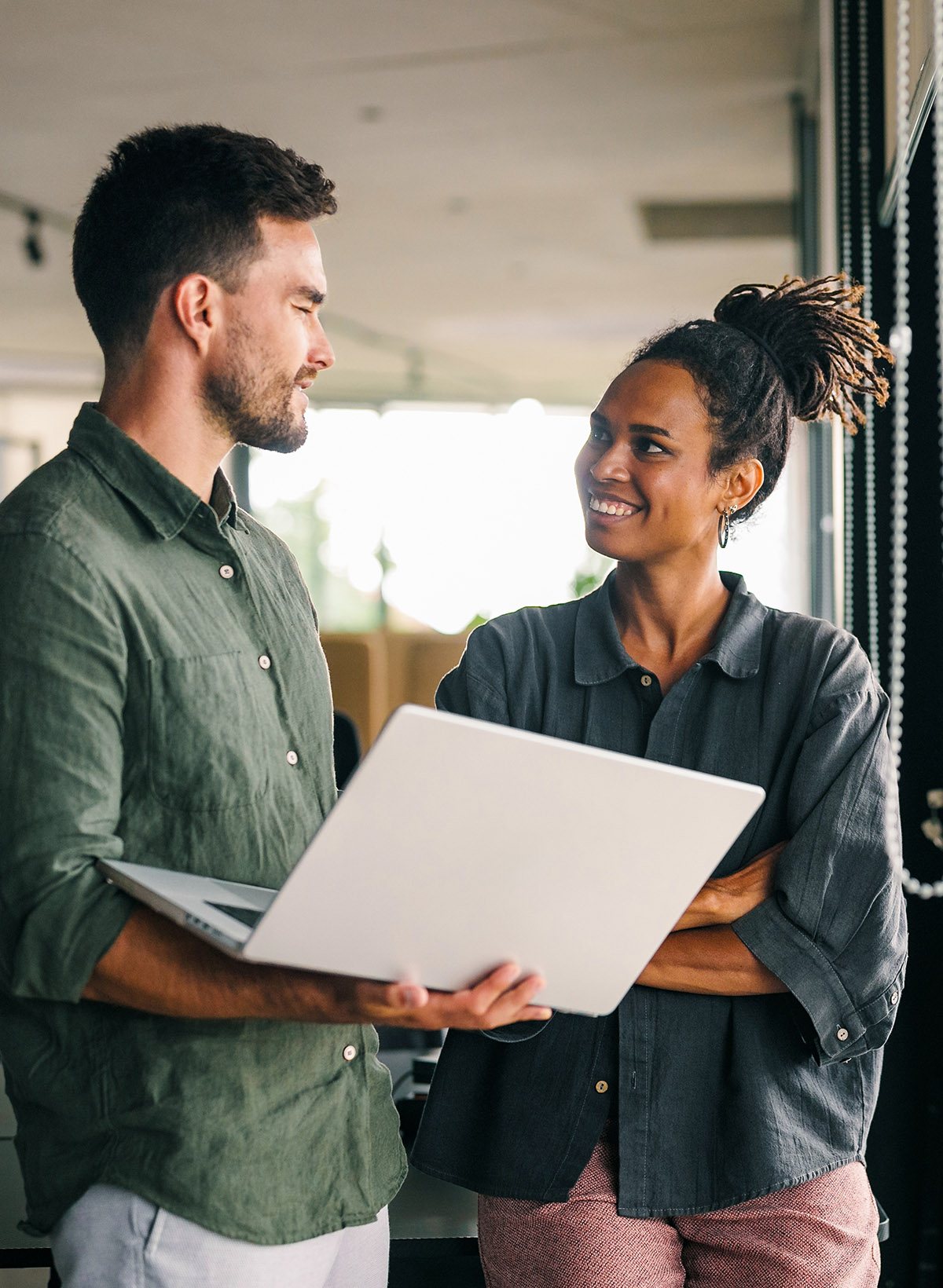 Diverse team of two business people working talking using tablet tech walking in corporate office.
